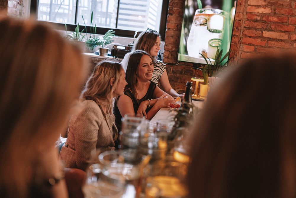 People enjoying drinks and conversation at a cozy restaurant with exposed brick walls and warm lighting.