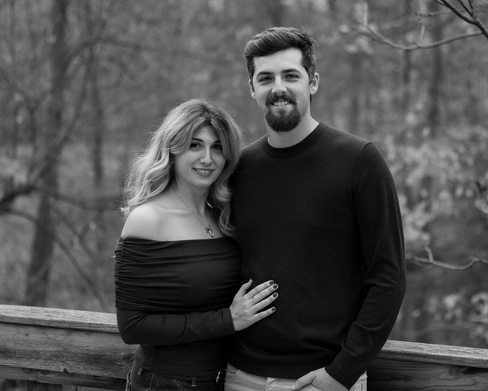 A romantic black and white photo series showing a couple embracing outdoors in a wooded setting.