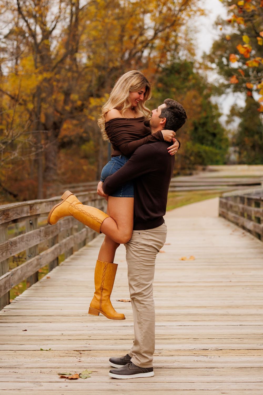 A romantic couple embraces on a wooden boardwalk surrounded by autumn foliage in a series of sequential photos.