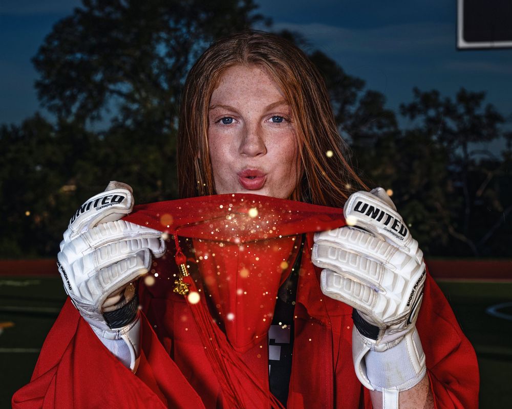 A person wearing white sports gloves holds a red sparkly surface against evening sky background.