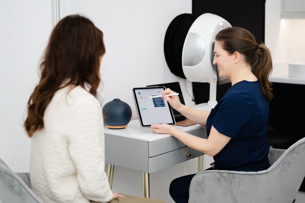 A medical consultation in progress with two people looking at a digital tablet in a clinical office setting.