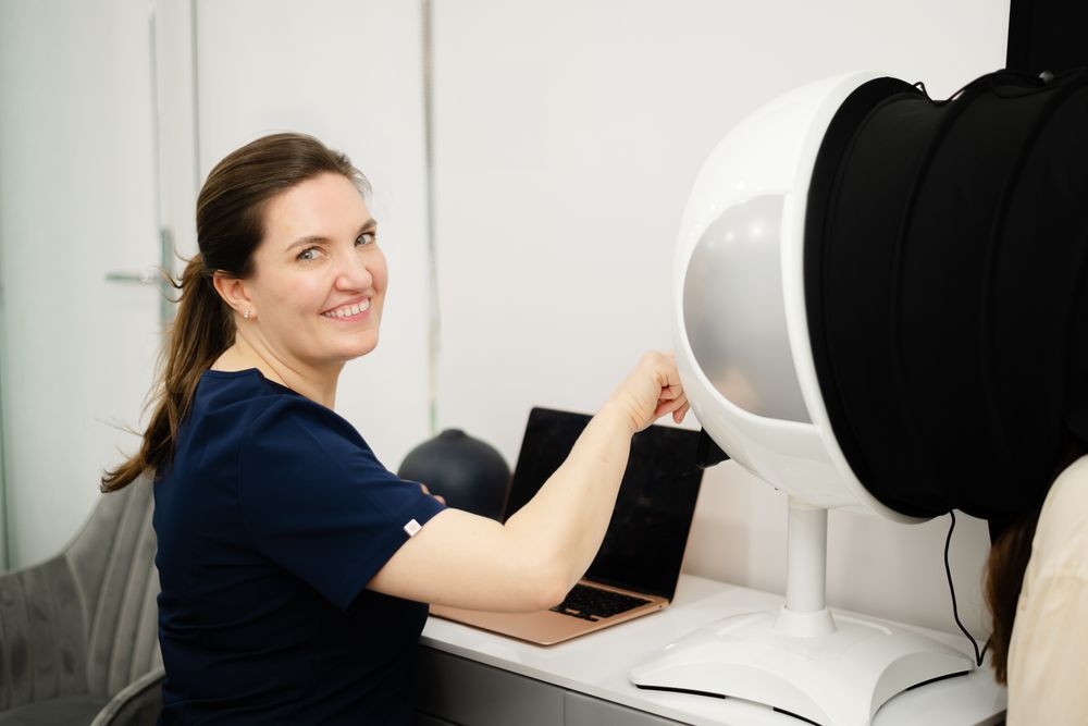 Healthcare worker operates advanced medical scanning equipment in a bright clinical setting.