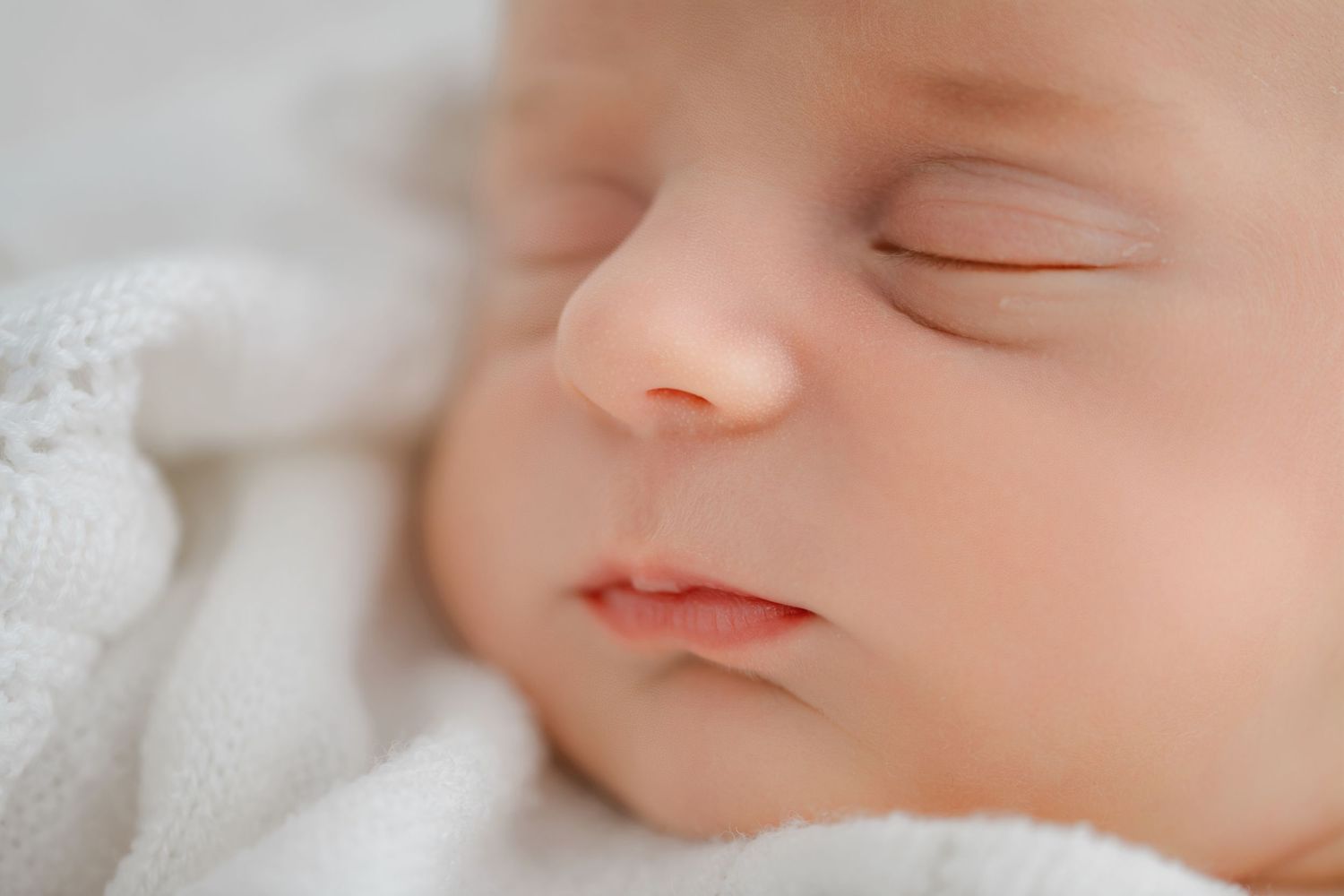 Close-up image of five sleeping newborn baby faces in a collage against white backgrounds.