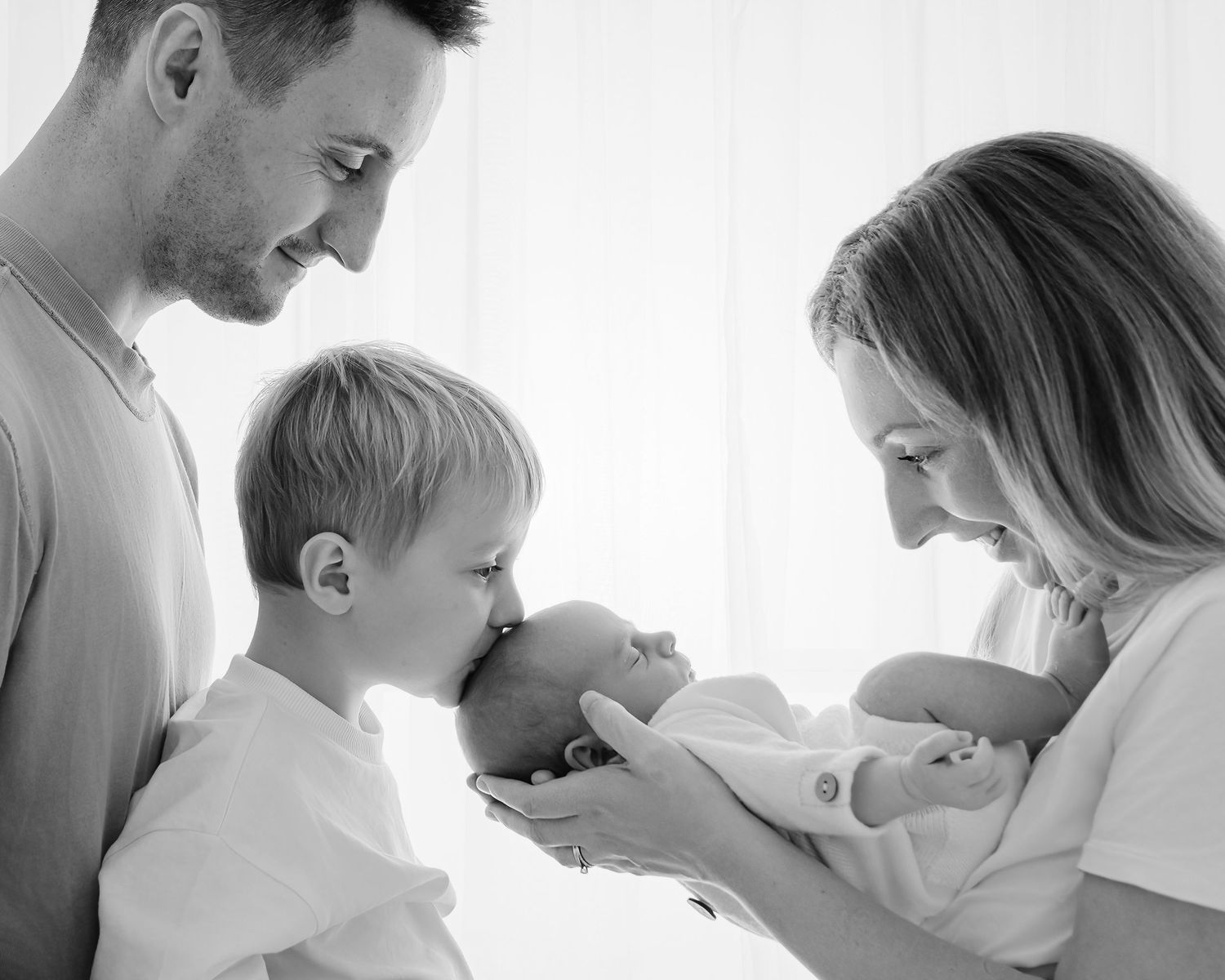 A series of black and white photos showing tender parenting moments between adult and child in soft natural light.