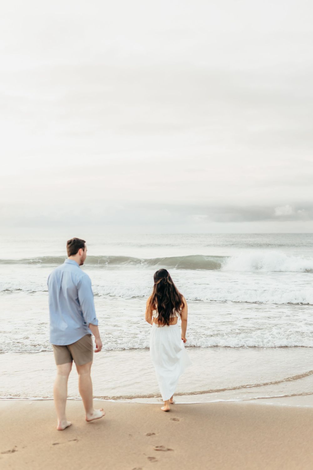 Couple walking together along a serene beach shoreline during sunrise. Wilmington NC. Wrightsville beach.