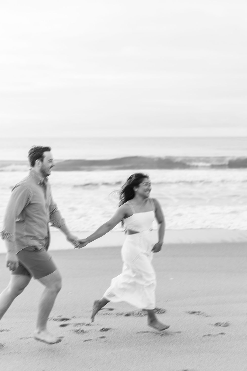 Energetic couple running and playing along the beach shoreline. Wilmington NC. Wrightsville beach.