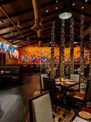 Interior dining room of Tiffins featuring carved wooden poles and ambient lighting with booth seating.