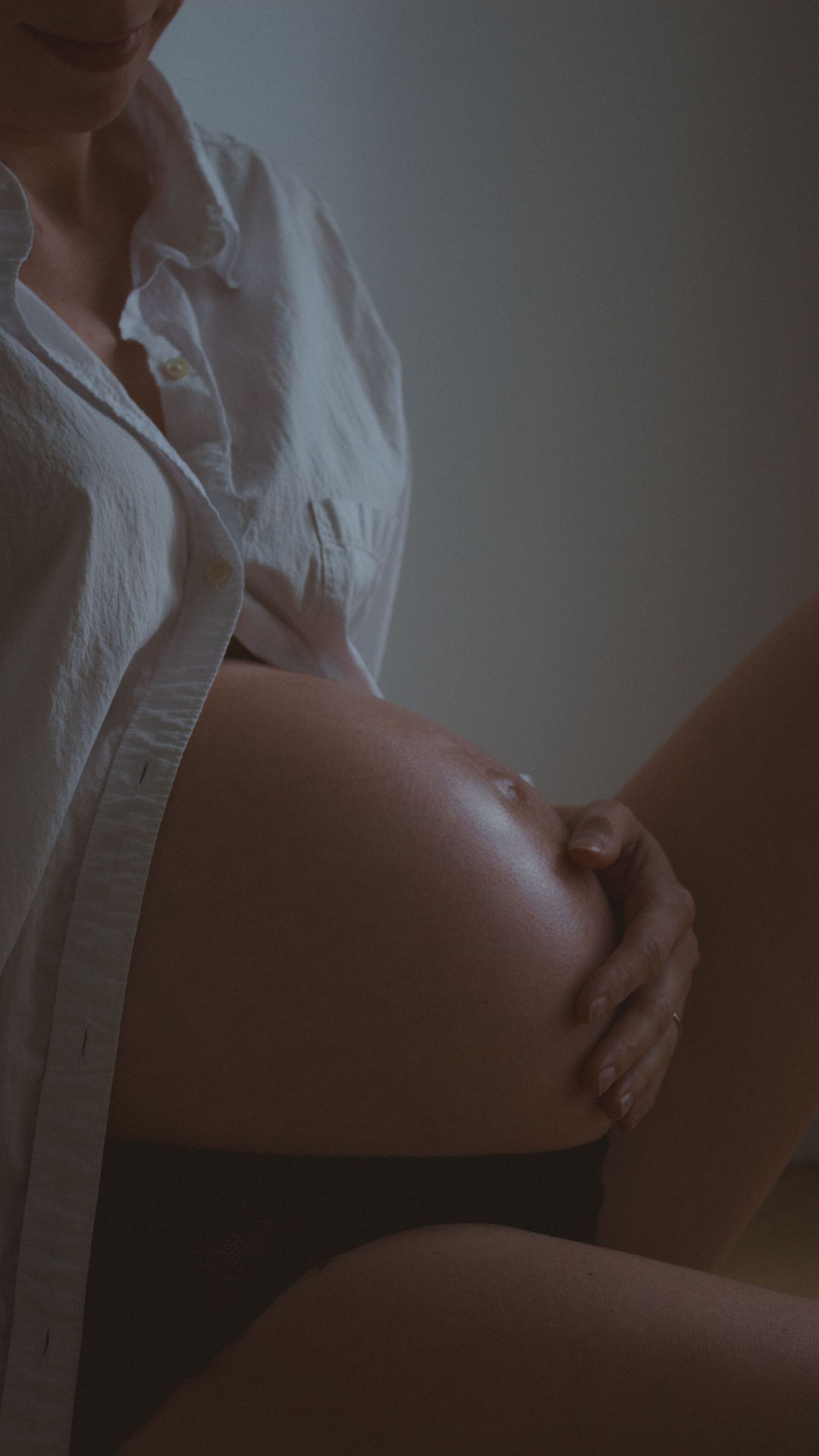pregnant belly close up shot with light reflecting off glowing skin