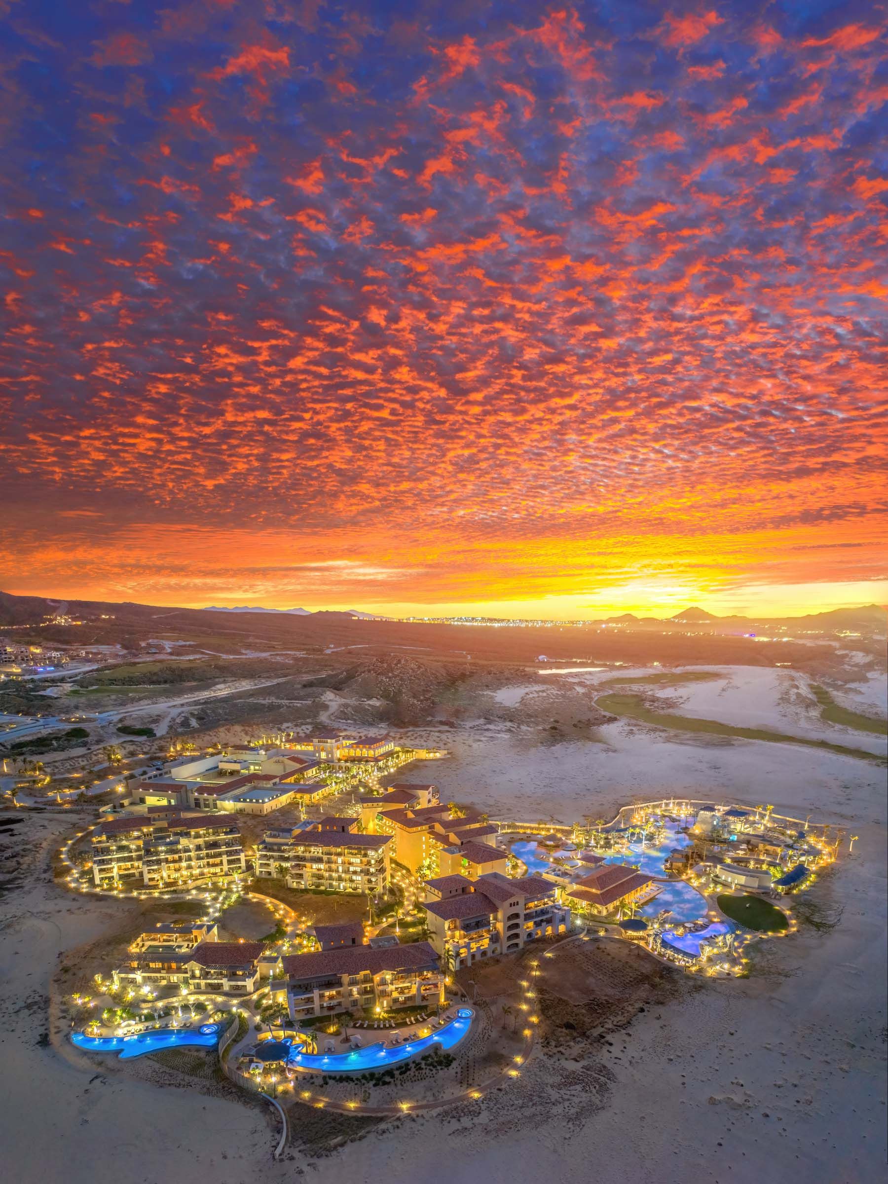 Stunning aerial view of resort complex under dramatic orange sunset sky. Grand Solmar Pacific Dunes Golf and Spa.