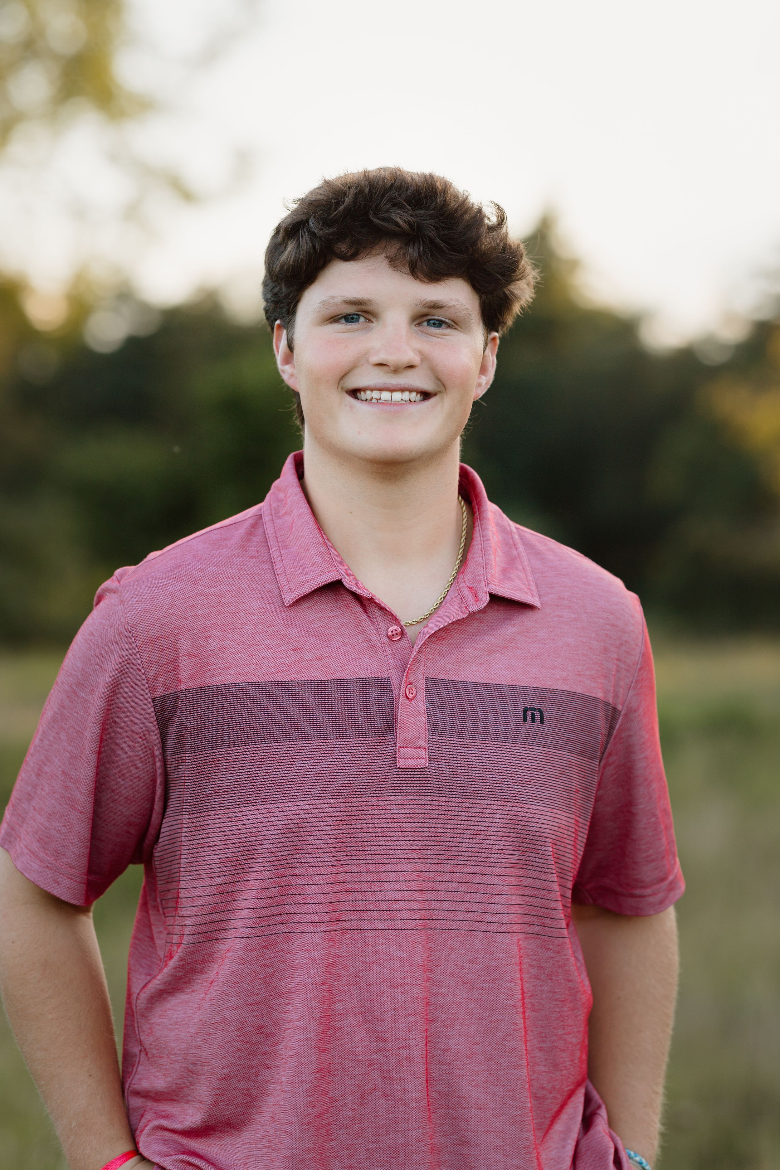 Portrait of person in pink striped polo shirt outdoors.