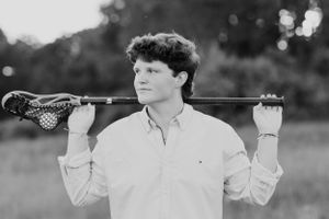 Black and white portrait with lacrosse stick held across shoulders.