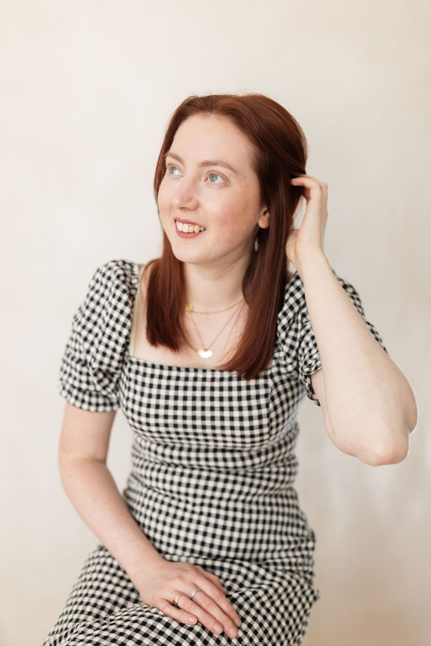 A studio portrait of a woman in a black turtleneck posed against a white backdrop.
