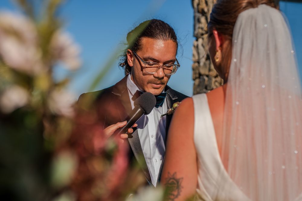 A wedding ceremony moment captured with natural lighting and floral elements in the foreground.