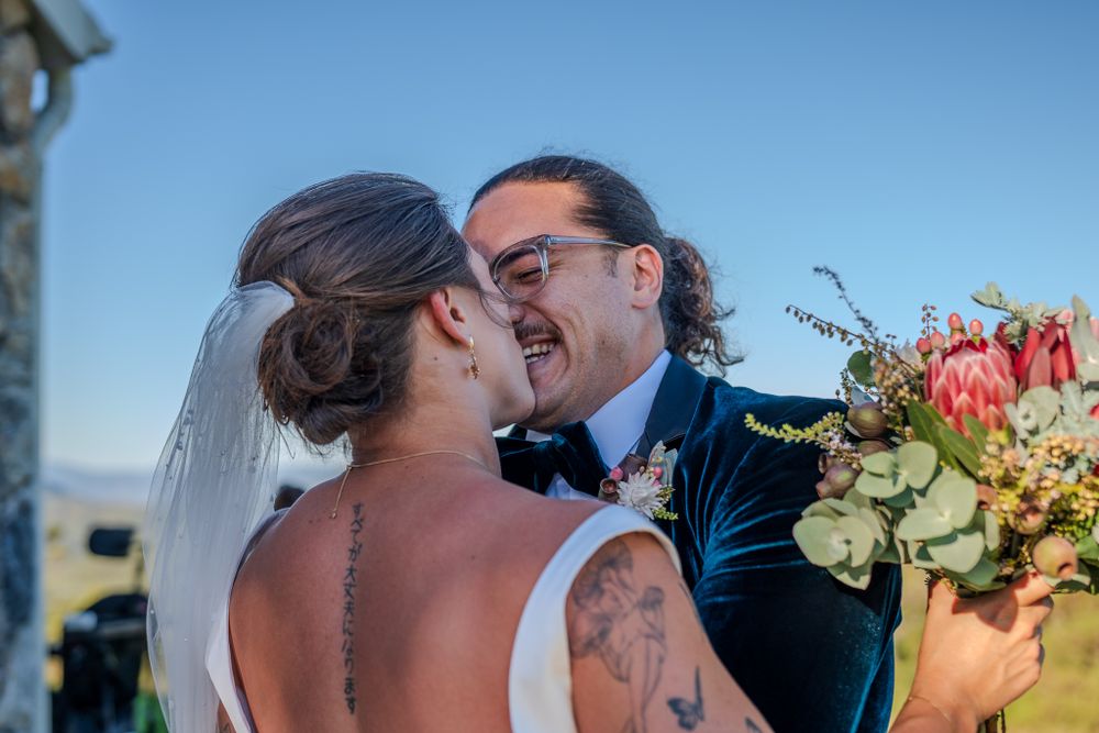 A intimate wedding moment with colorful bouquet against blue sky backdrop.