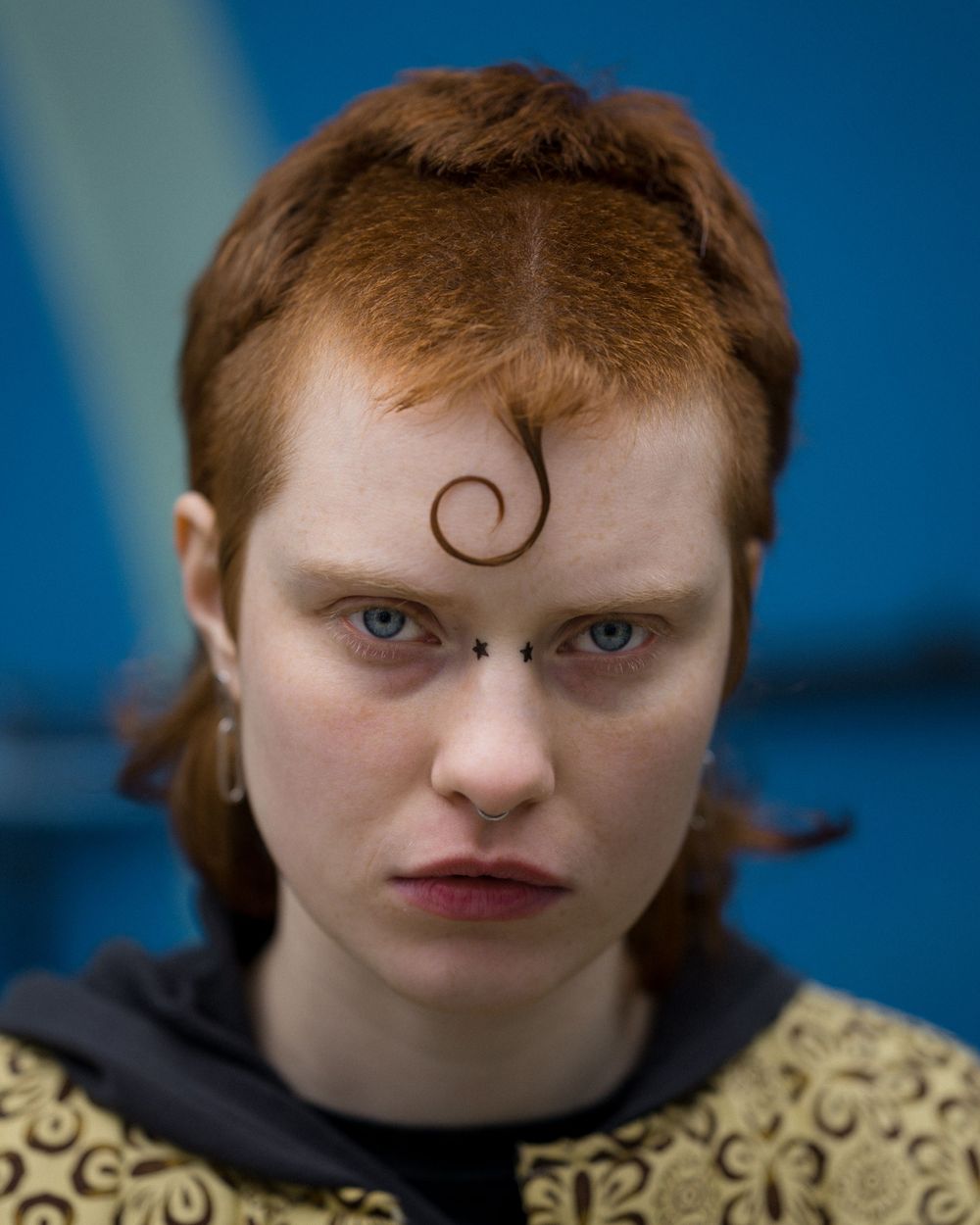 Bold portrait of a person with striking red hair and a fierce gaze— style of fashion editorials and creative portraits