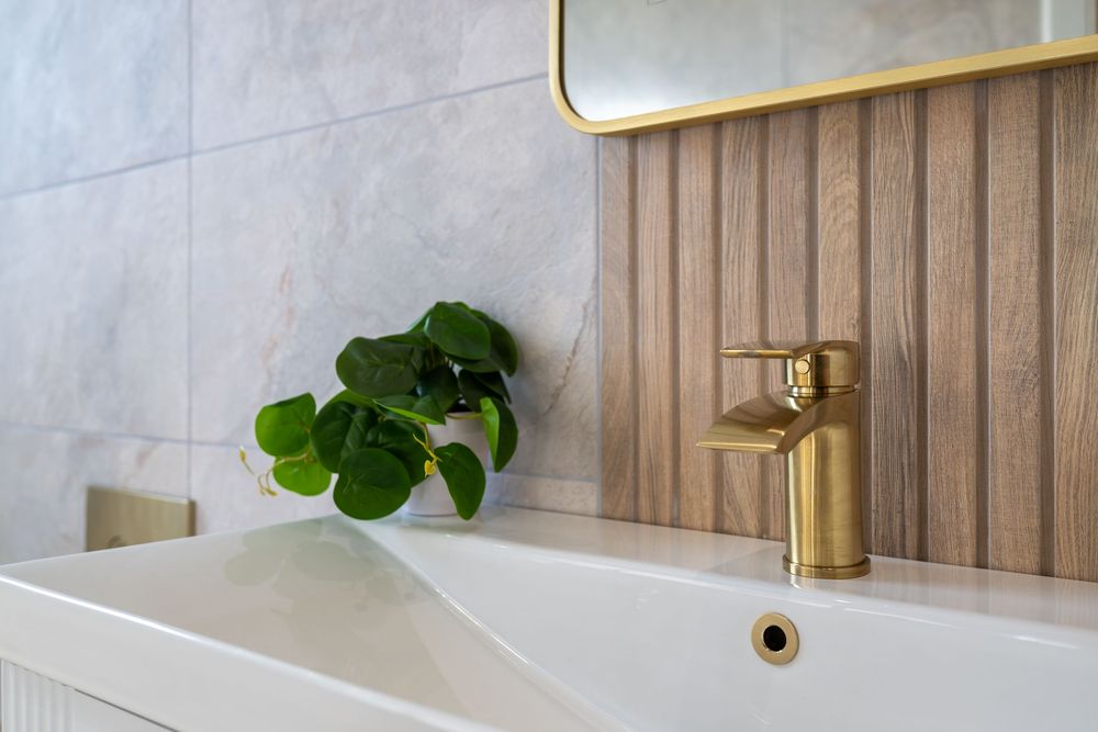 Modern bathroom interior with wooden wall paneling, brass fixtures, and green plants creating a spa-like atmosphere.