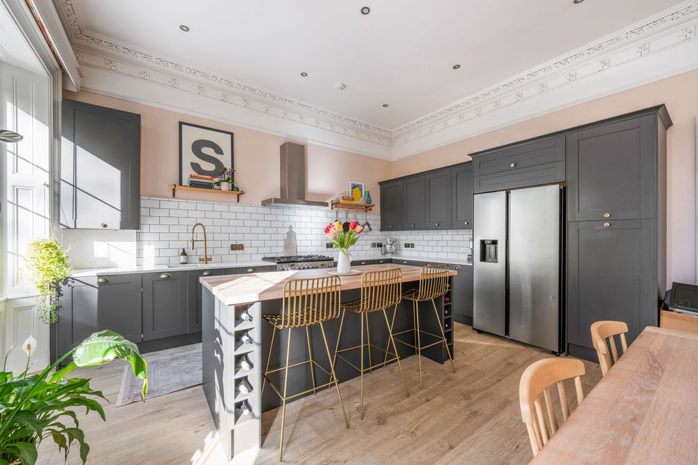 Modern open concept living and dining area with dark kitchen cabinets and wooden flooring throughout.