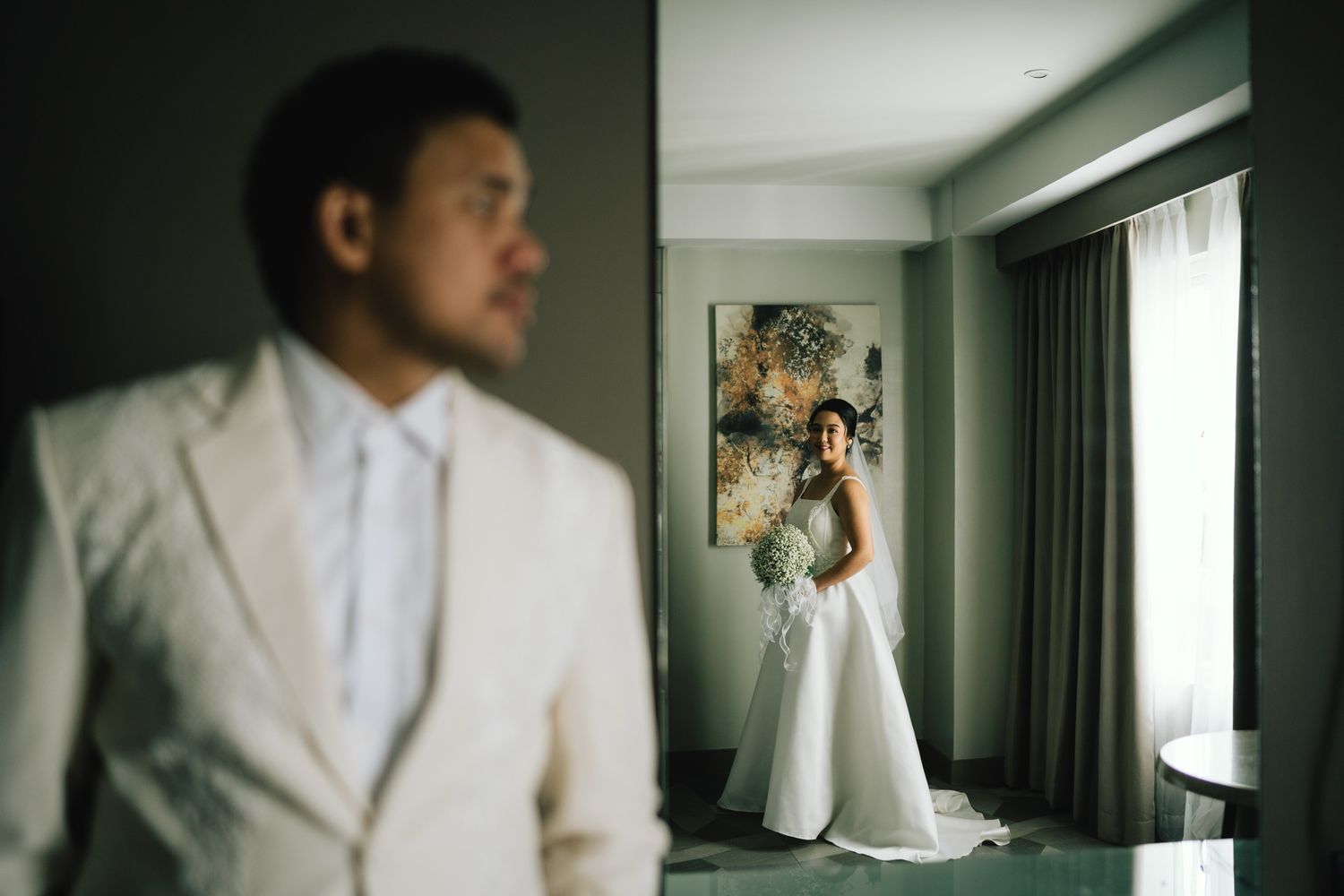 Artistic wedding photo showing silhouettes and reflections in an elegant hotel room setting.