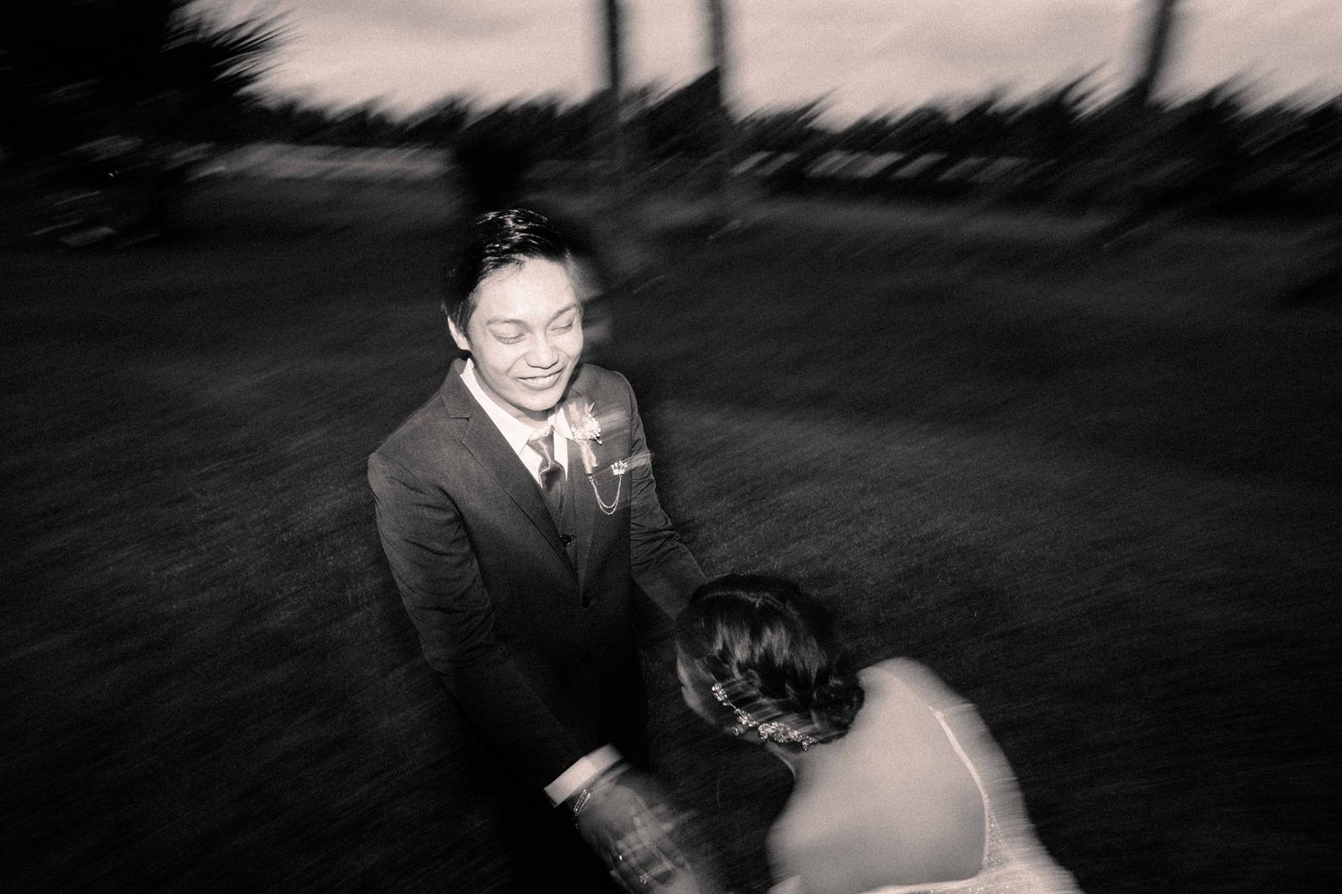 Black and white motion blur photograph capturing an intimate moment outdoors.