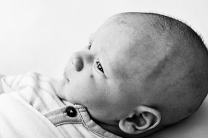 Black and white close-up portrait of a peaceful newborn baby gazing upward, showcasing delicate features.
