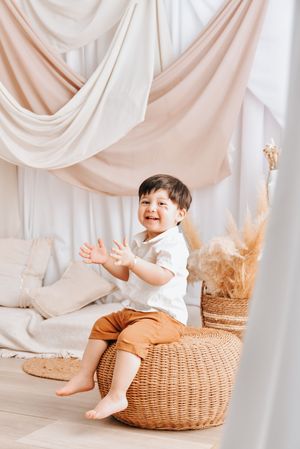 A collage of photos showing a small child sitting on a woven basket against a white draped fabric background.