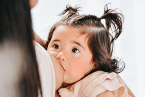 A child with messy hair looks up with a playful expression while sitting against a white background.