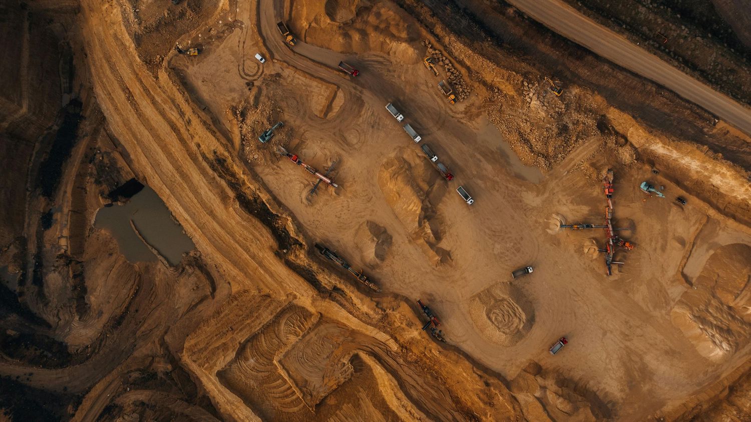 Aerial view of a quarry or mining site with winding brown and beige terrain patterns created by excavation.