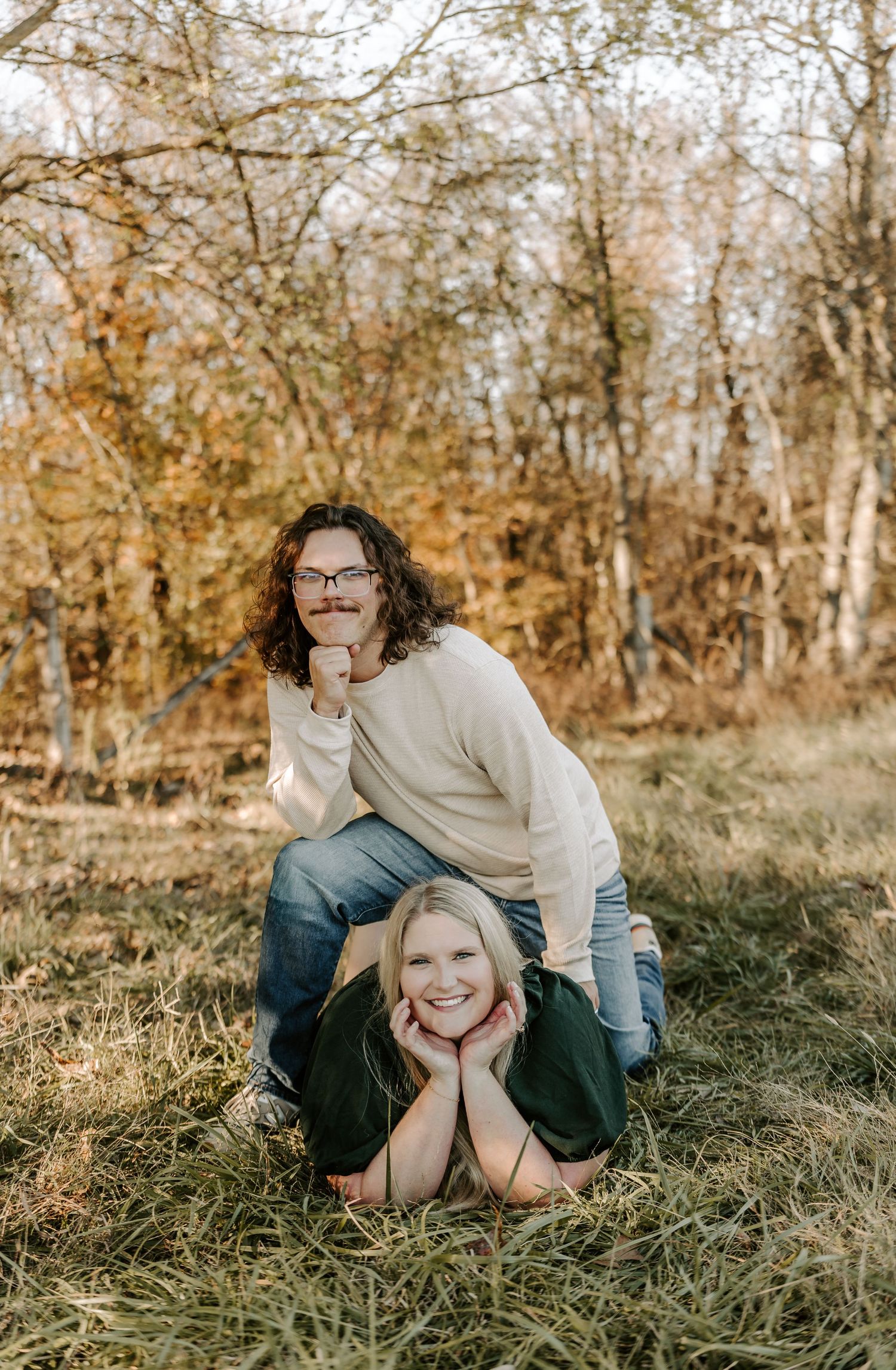 Couple having fun and playing on grassy hill in fall setting.