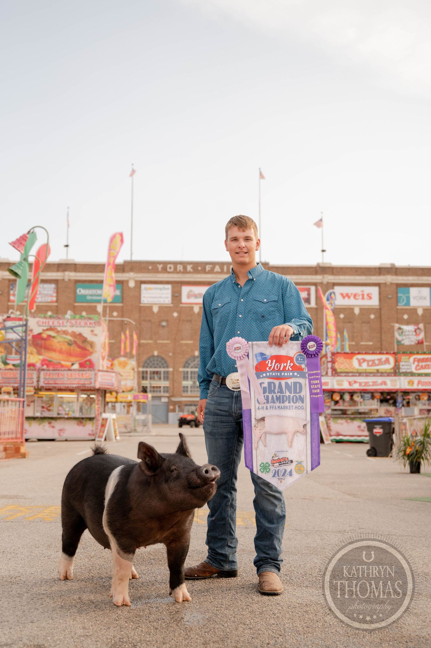 Hampshire pig with award ribbons at county fair stands in front of brick exhibition building.