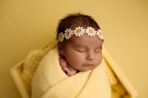 Sleeping newborn girl wrapped in yellow knit blanket wearing a daisy flower headband -- Sara Prue Photography Denver