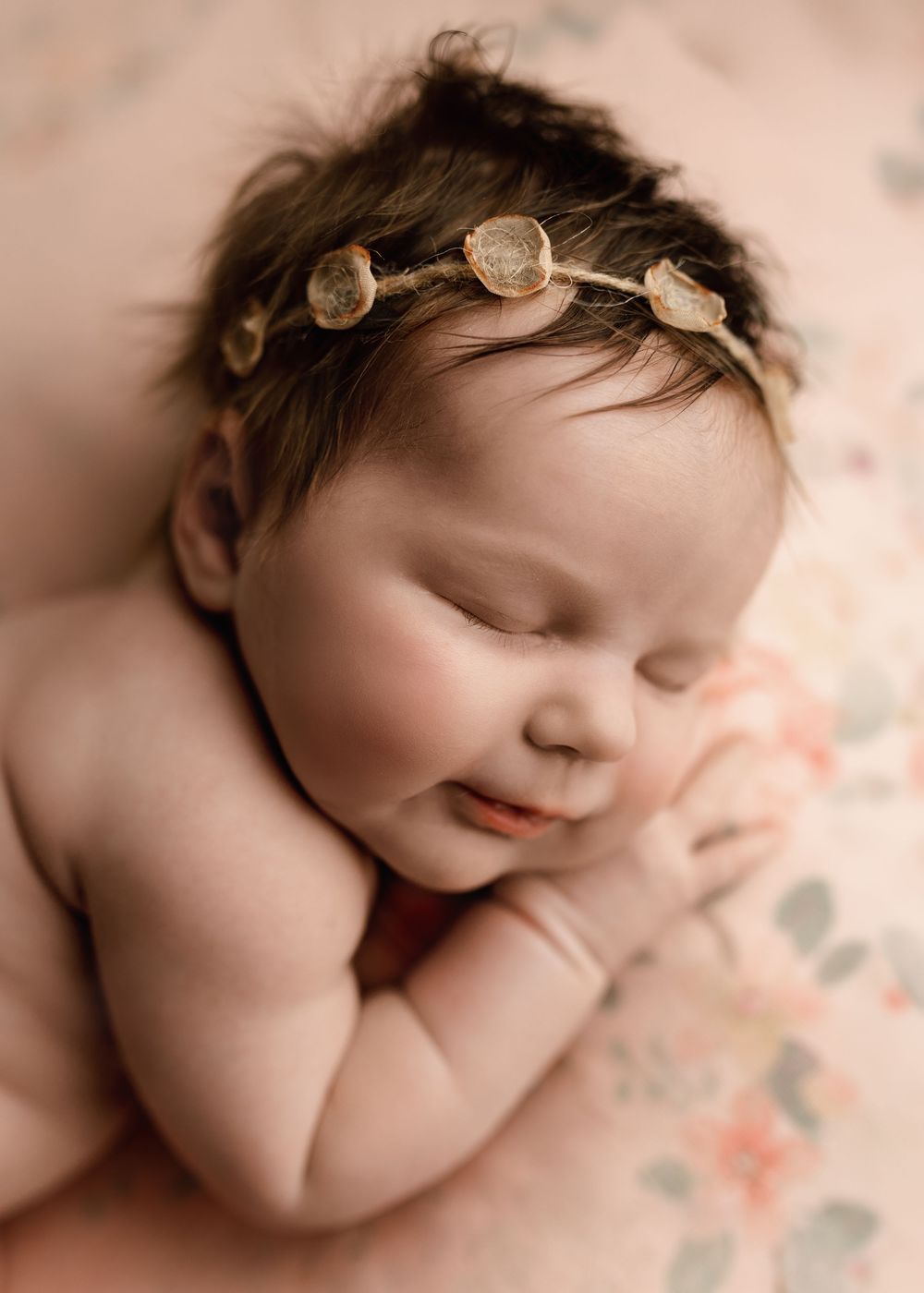Peaceful sleeping newborn baby girl wearing a delicate floral headband, resting on a soft floral blanket -- Sara Prue Photography Denver