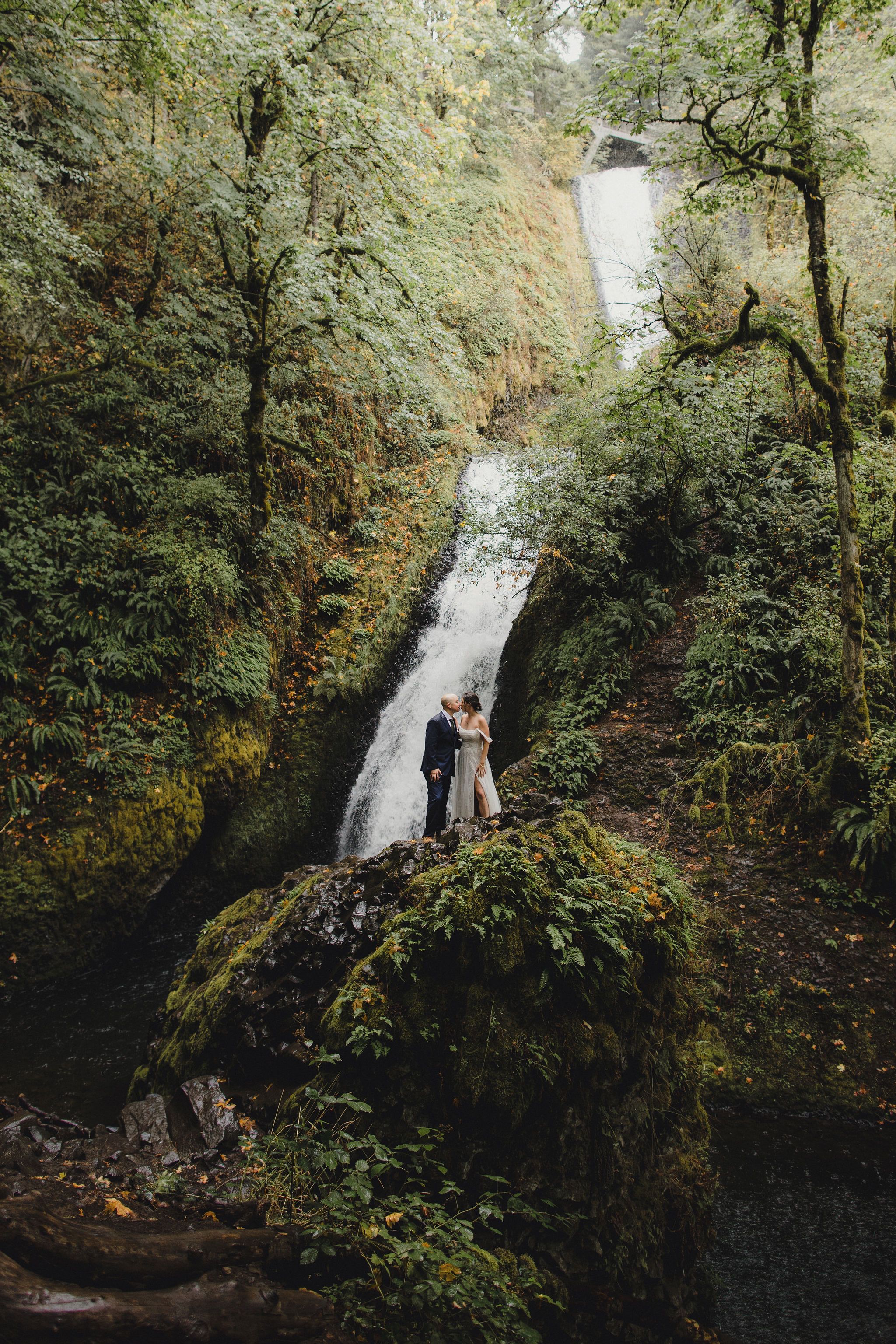Full view of bridal veil falls in Oregon with a couple that has just gotten married.