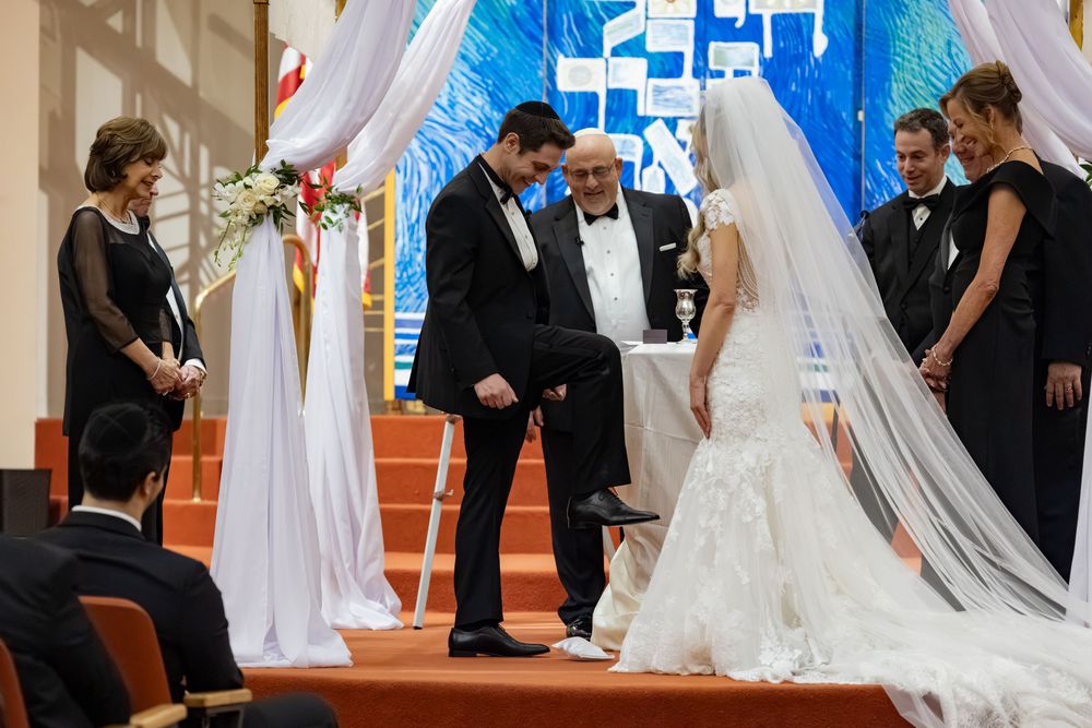 Jewish wedding ceremony under a chuppah with bride, groom, and officiant at an elegant synagogue venue.