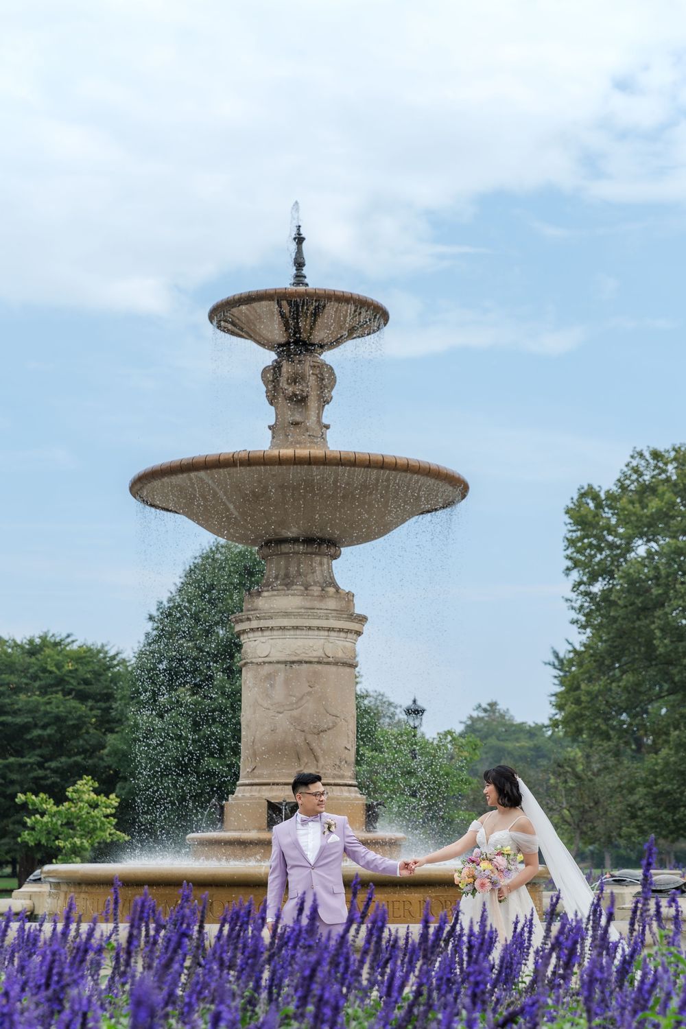 Candid wedding photography of groom leading his bride by the water fountain in gage park in downtown Hamilton, Ontario.
