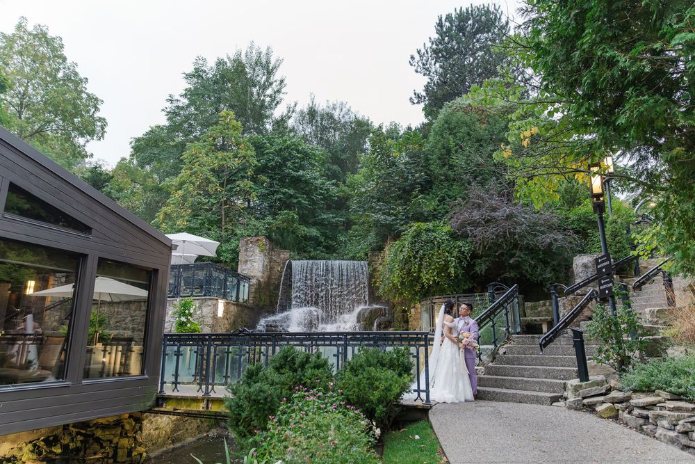 Bride and groom standing together beside the waterfall at the ancaster in during their wedding photos in ancaster, ontario.