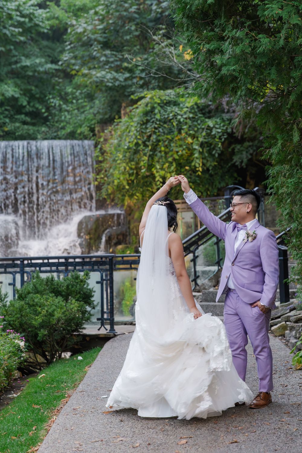 Groom twirling his bride by the waterfall at the ancaster mill during their wedding in hamilton, ontario.