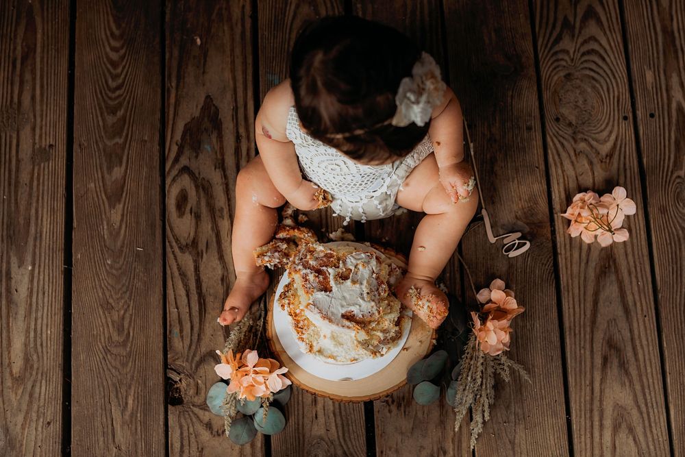 A rustic cake smash photography setup with a wooden backdrop and teal decorative elements.