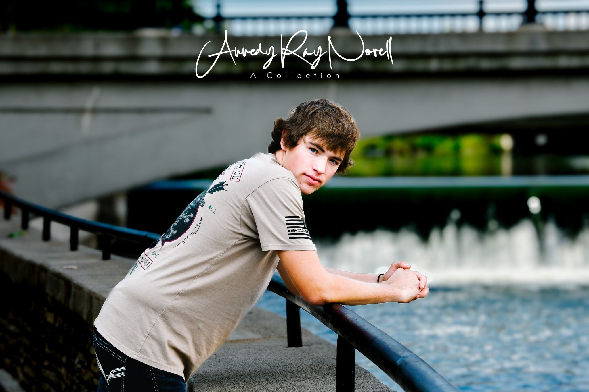 Teen boy leaning on metal railing near fountain, casual senior portrait by Amanda Ray Wood Photography.