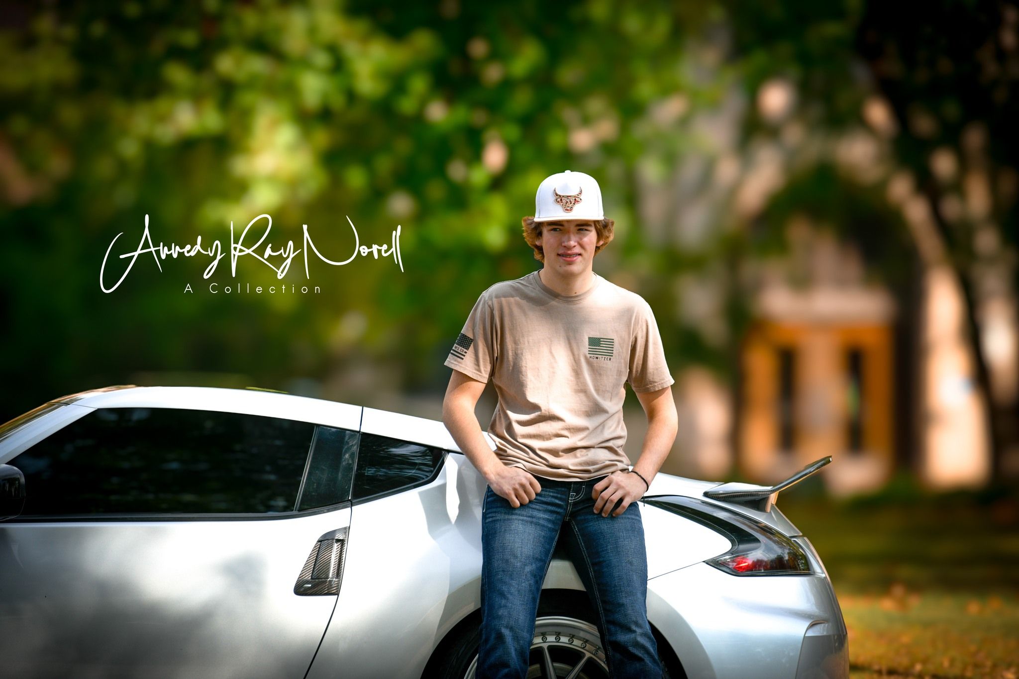 Young man in white cap and beige shirt leaning on silver sports car outdoors in a professional photo shoot.