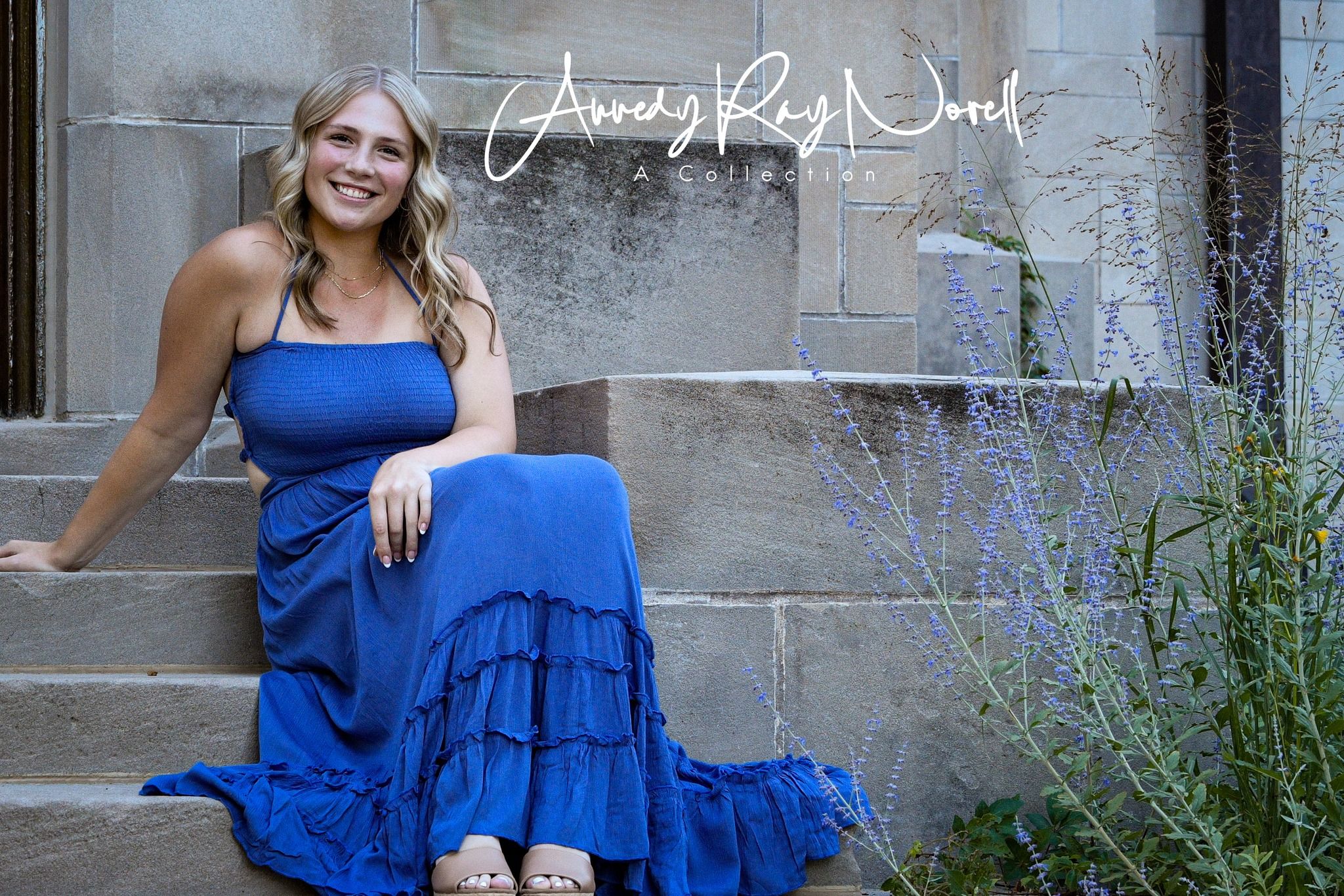 Woman in blue ruffled maxi dress sitting on stone steps smiling outdoors.