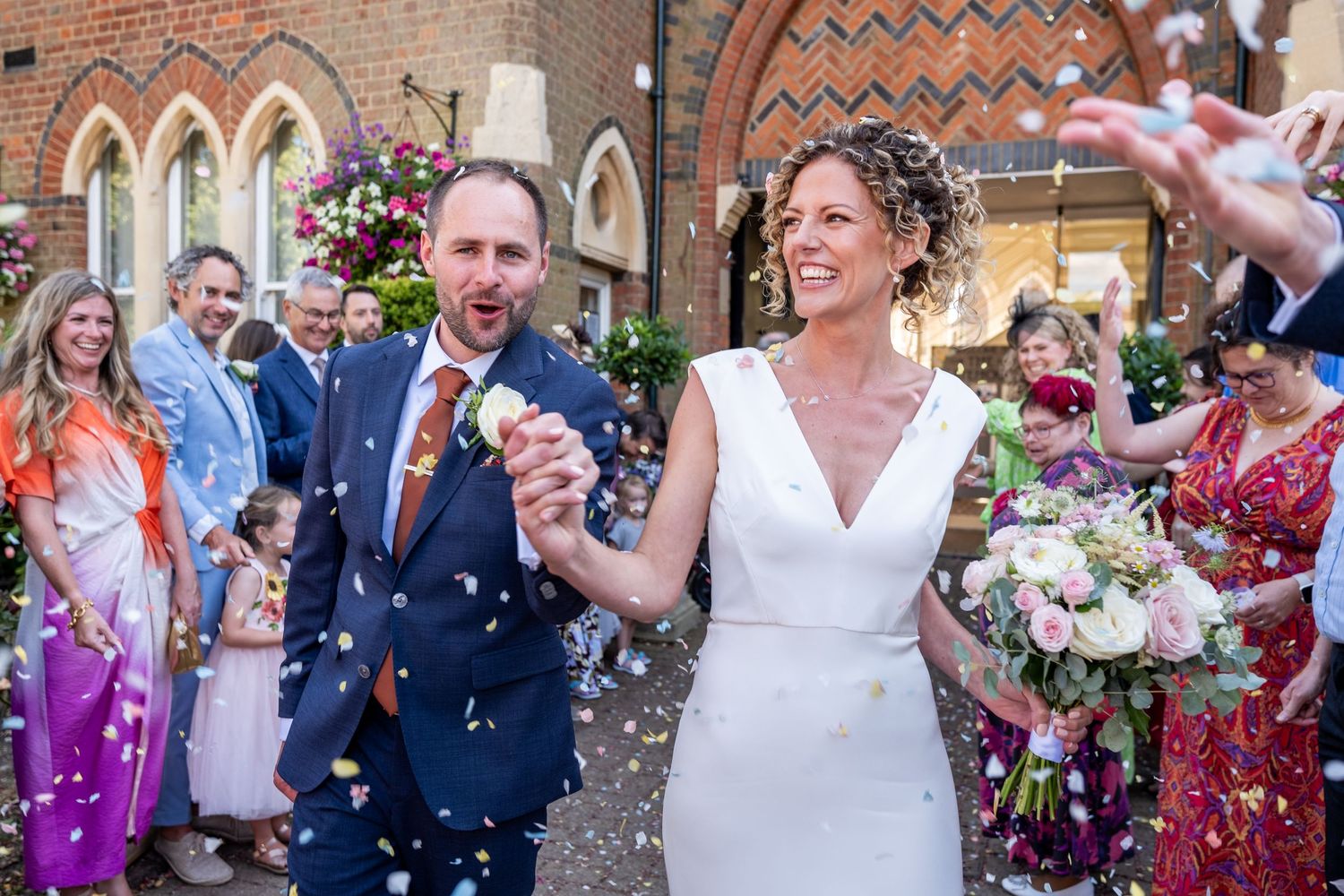 A couple in wedding attire walks together through a lush garden setting during their Islington ceremony.