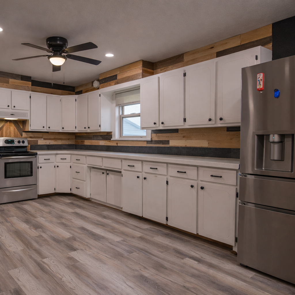 Modern kitchen with white cabinets, dark countertops, stainless steel appliances, and gray wood-look flooring.