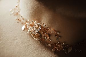 Elegant gold filigree bridal hair vine with crystal beads and floral details on soft beige fabric.