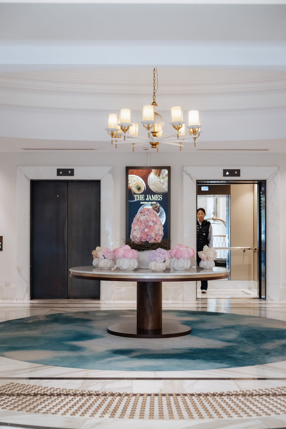 Elegant hotel lobby at The James with a round marble table, crystal decor, and gold chandelier.