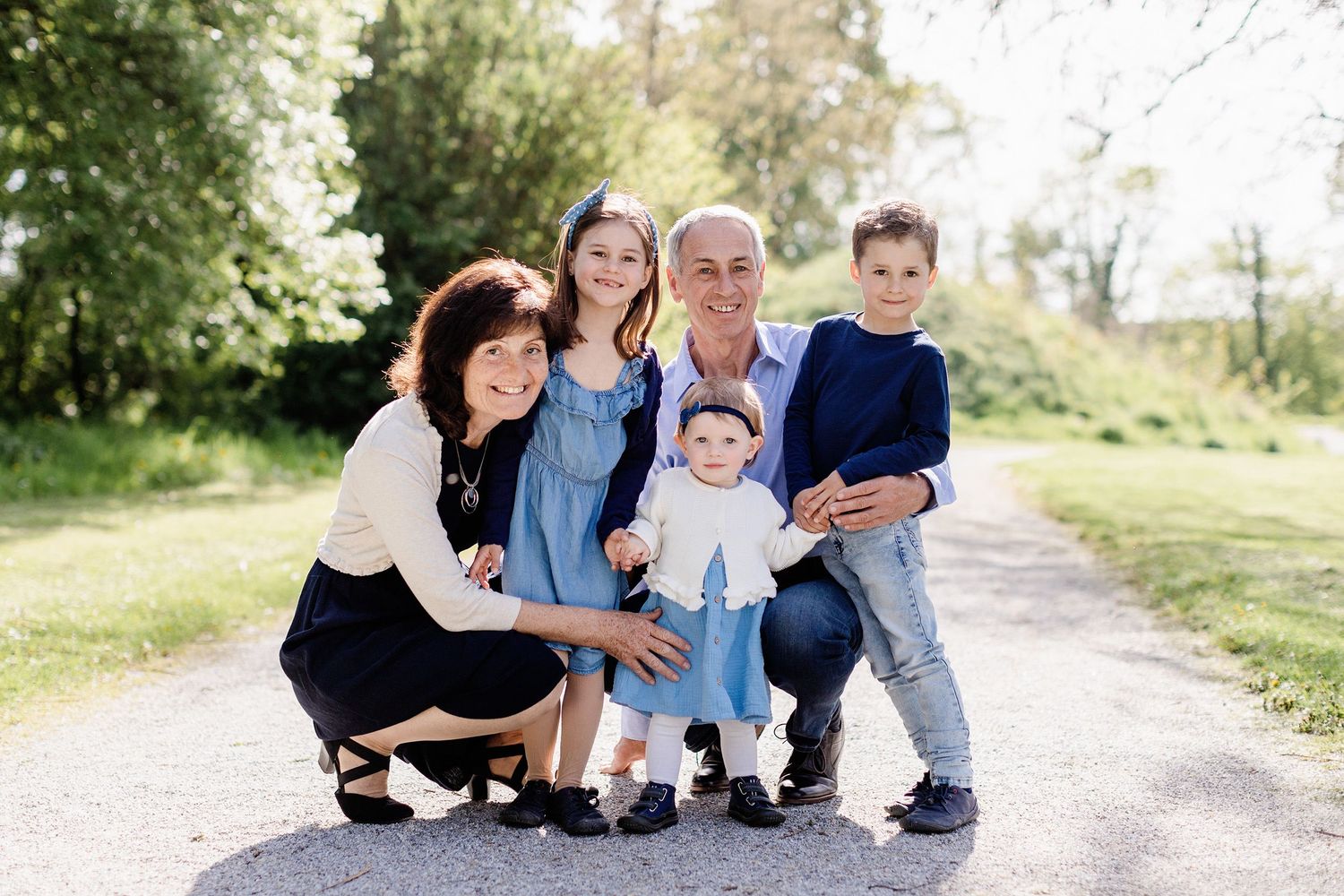 Eine vierköpfige Familie sitzt während eines Fotoshootings im Freien an einem freundlichen Tag auf einer Wiese zusammen.