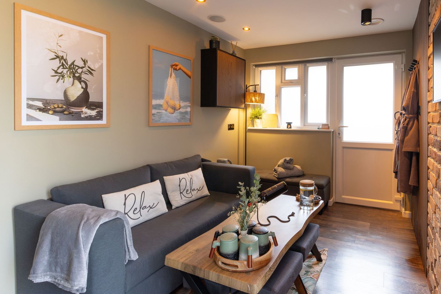 Relaxation room at garden spa in Bedfordshire with grey sofa, wooden coffee table and framed wall art.