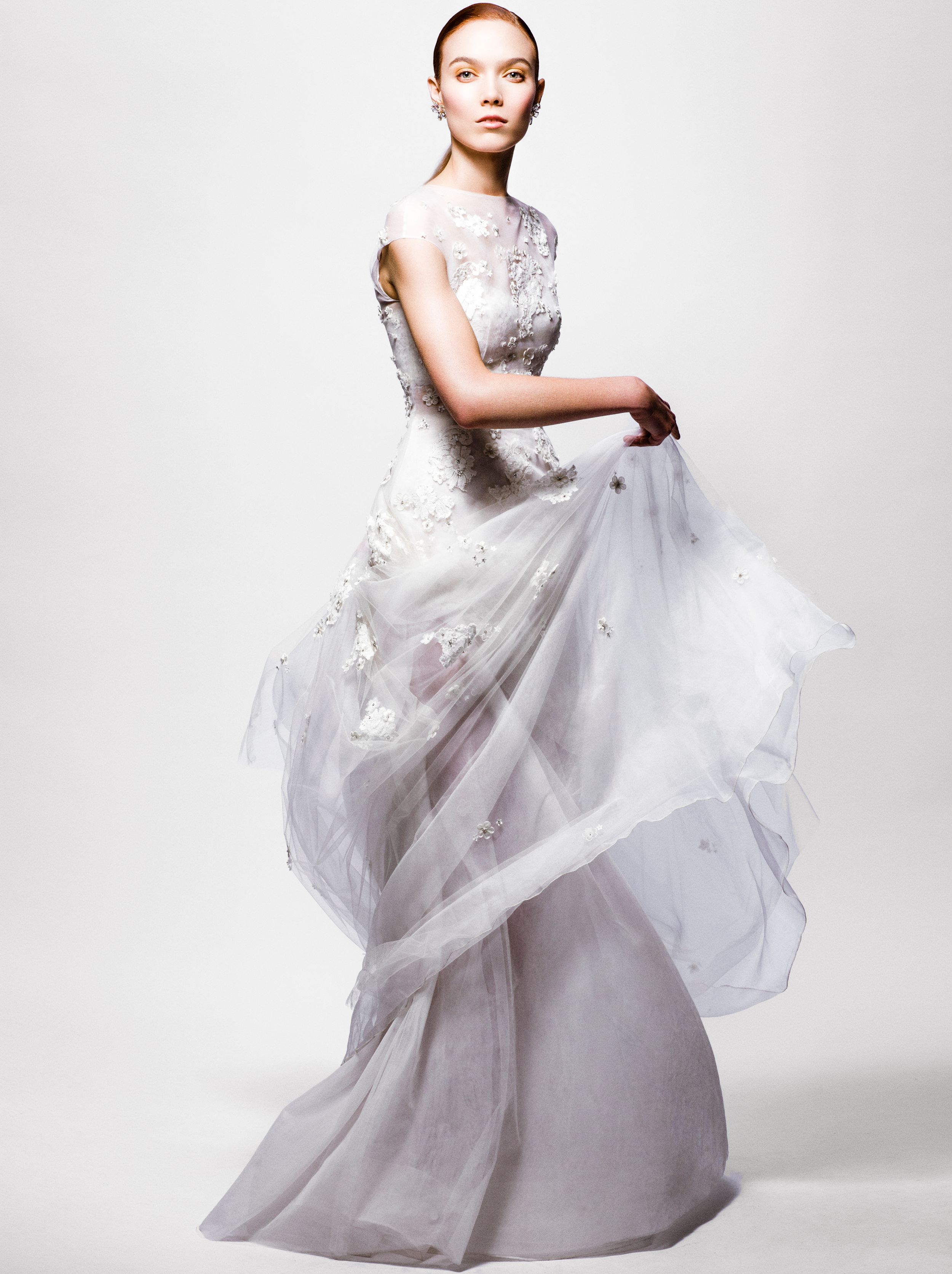 Elegant white bridal gown with floral embroidery and flowing tulle skirt on a model against a white background.
