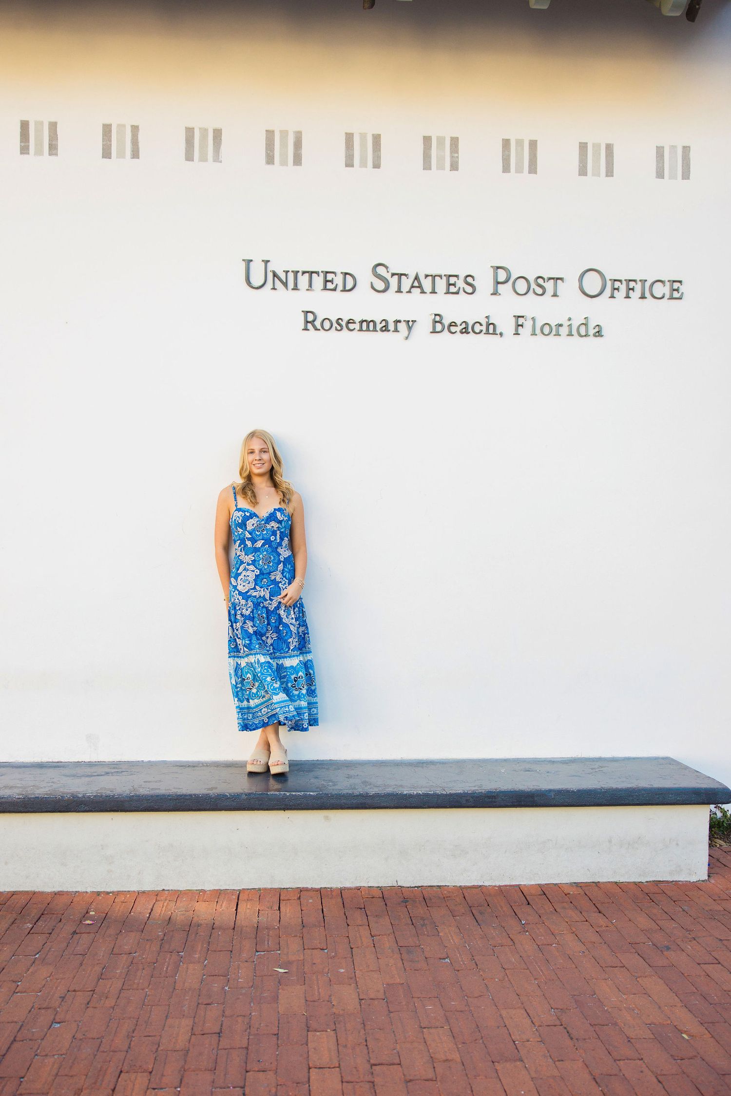 Woman in blue floral maxi dress posing outside United States Post Office in Rosemary Beach, Florida.