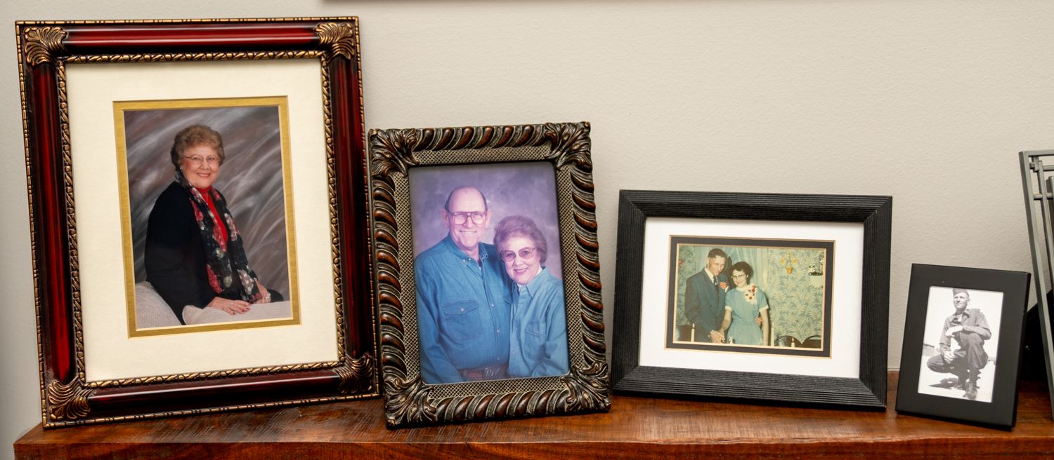 Collection of family photographs displayed in ornate frames on wooden surface.