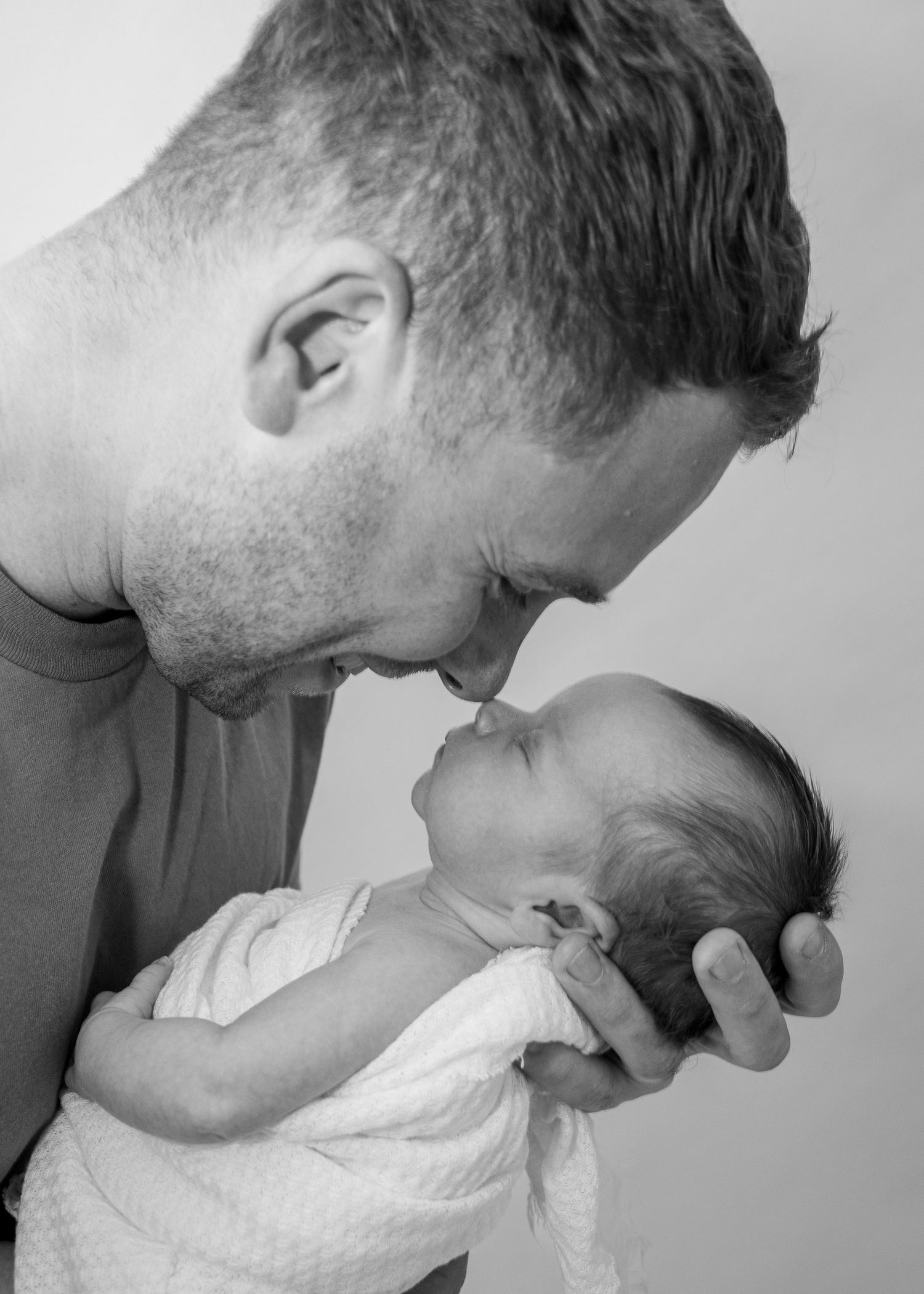 Black and white intimate portrait of parent leaning over sleeping baby.
